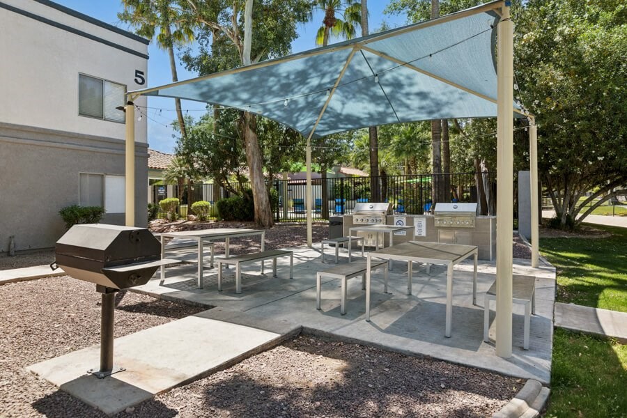a patio with tables and chairs and a grill