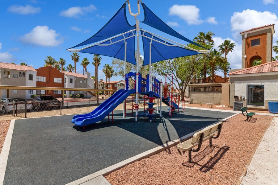 a playground with a blue slide and umbrella at villas at houston levee west apartments