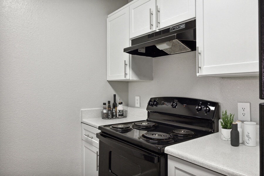 a kitchen with white cabinets and a black stove top oven