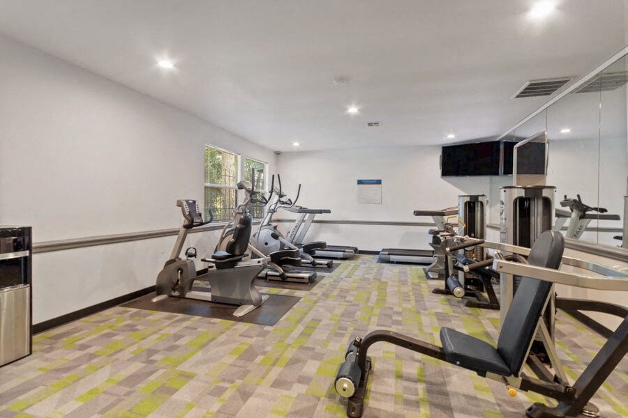 Fitness center with cardio machines, weight machines, and large mirrors