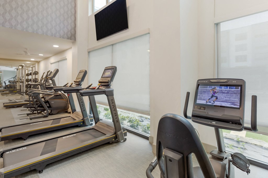 a room filled with cardio equipment and a flat screen tv
