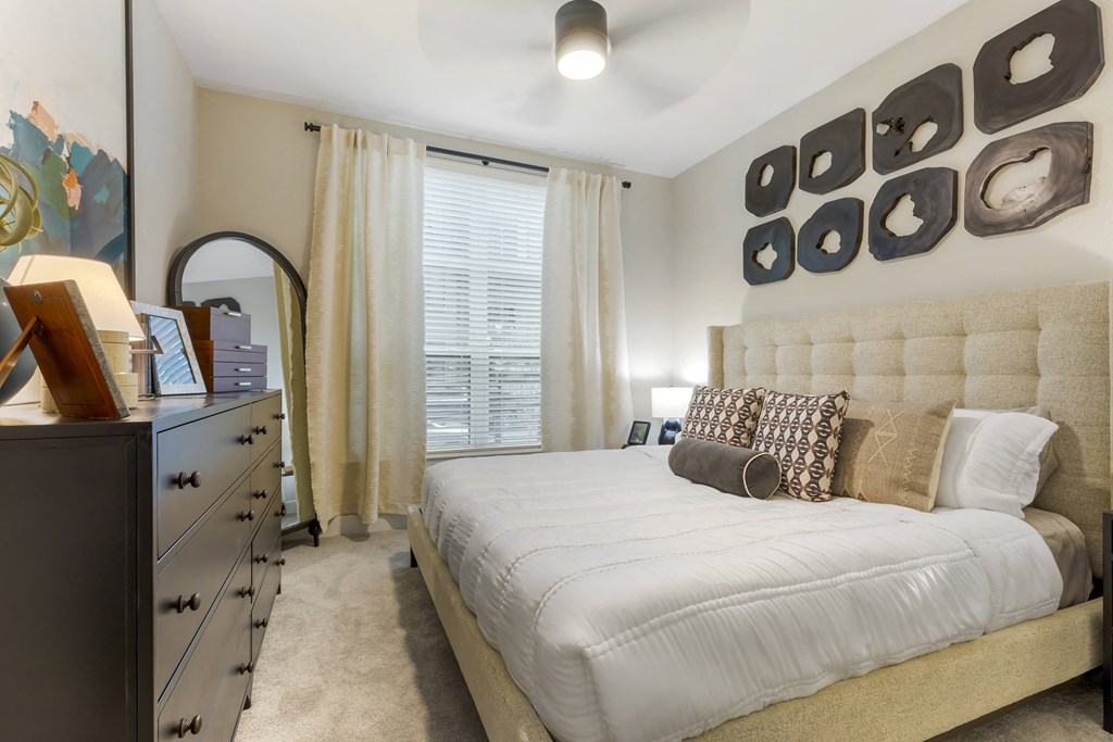 a bedroom with a large bed and a dresser with a mirror