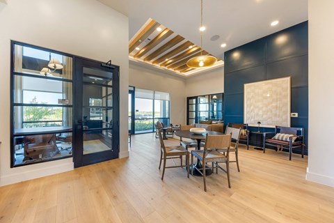 a dining room with a table and chairs and large windows
