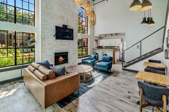 Clubhouse lounge area with fireplace and TV on the wall between large windows