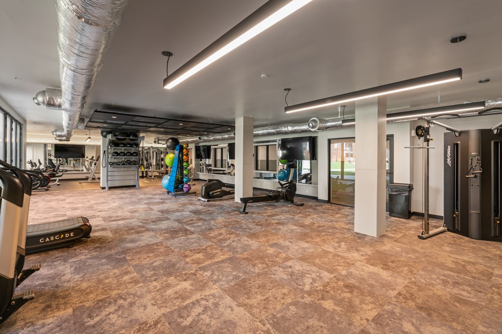 A gym with a variety of equipment including treadmills, weights, and exercise machines.