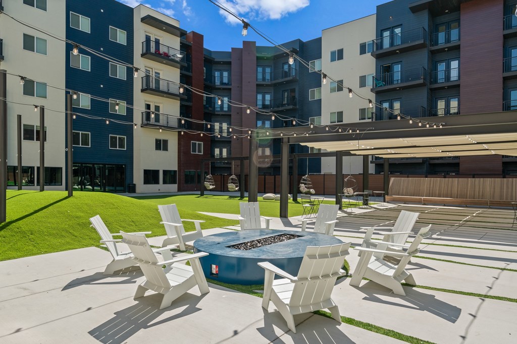 A pool surrounded by white chairs in a courtyard.