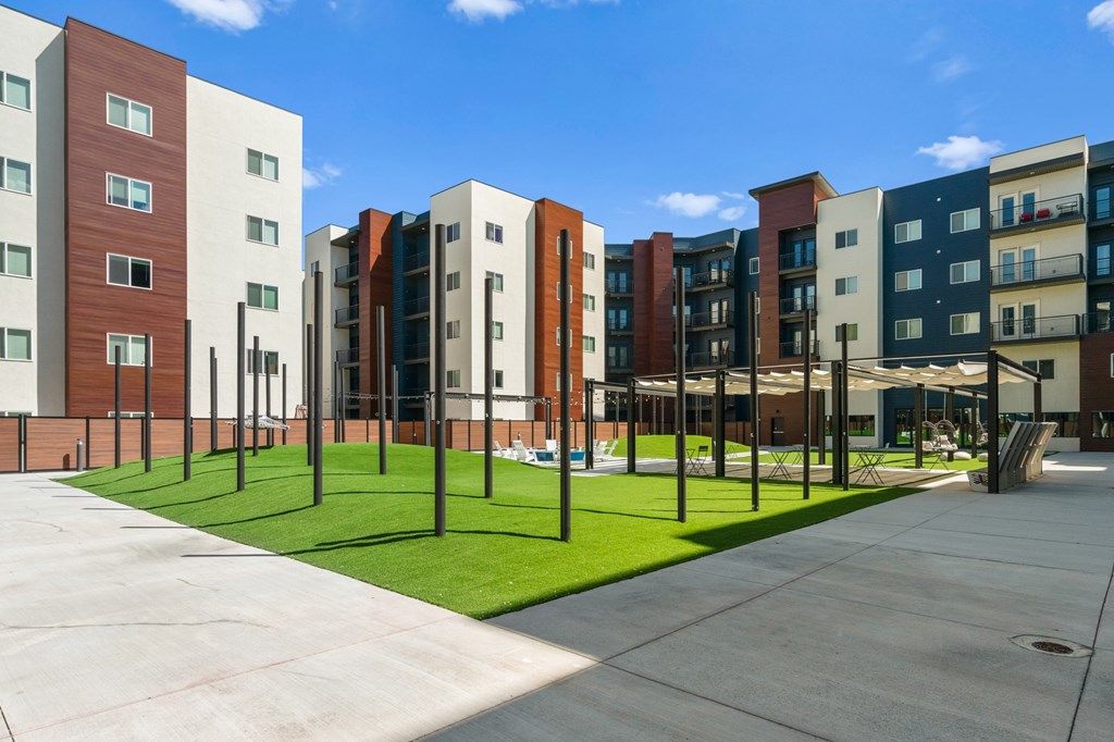 A row of modern apartment buildings with green grass in front.