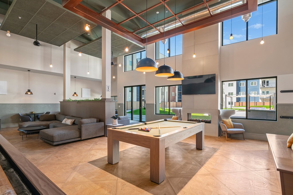 A billiard table is in the middle of a room with a pool table and a foosball table.