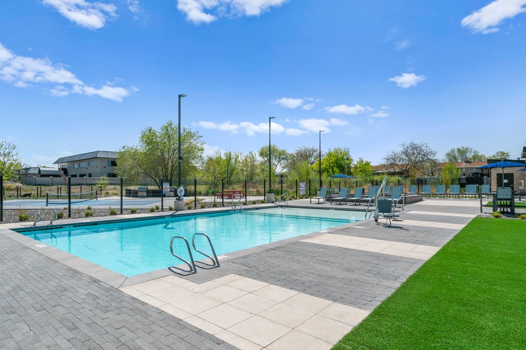 A swimming pool surrounded by a grassy area and a fence.