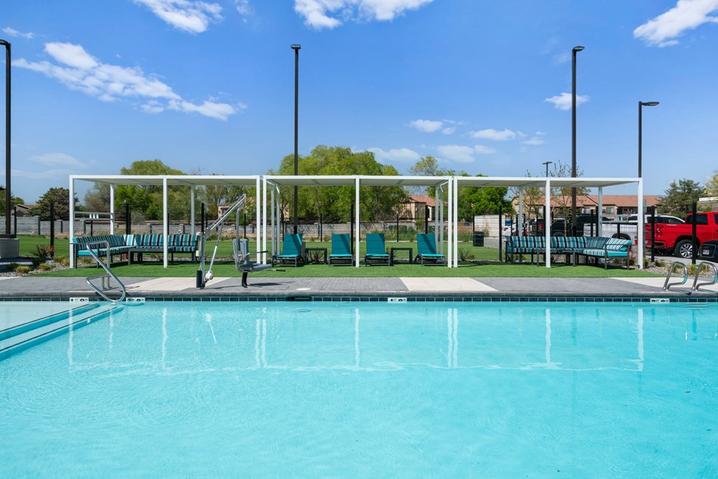 A swimming pool with a diving board and a green lawn.