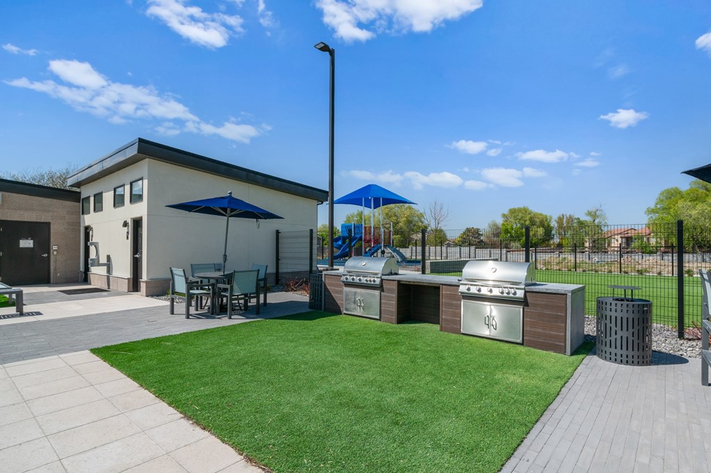 A small building with a blue umbrella and a playground in the background.