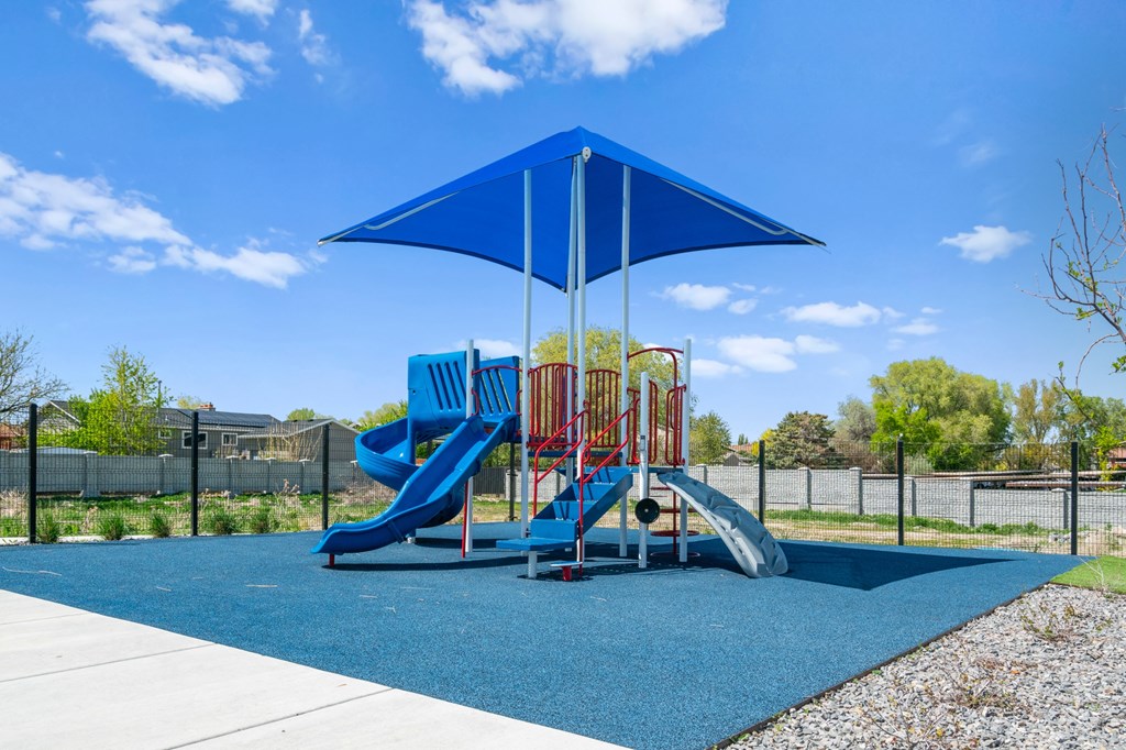A playground with a blue umbrella and a red slide.