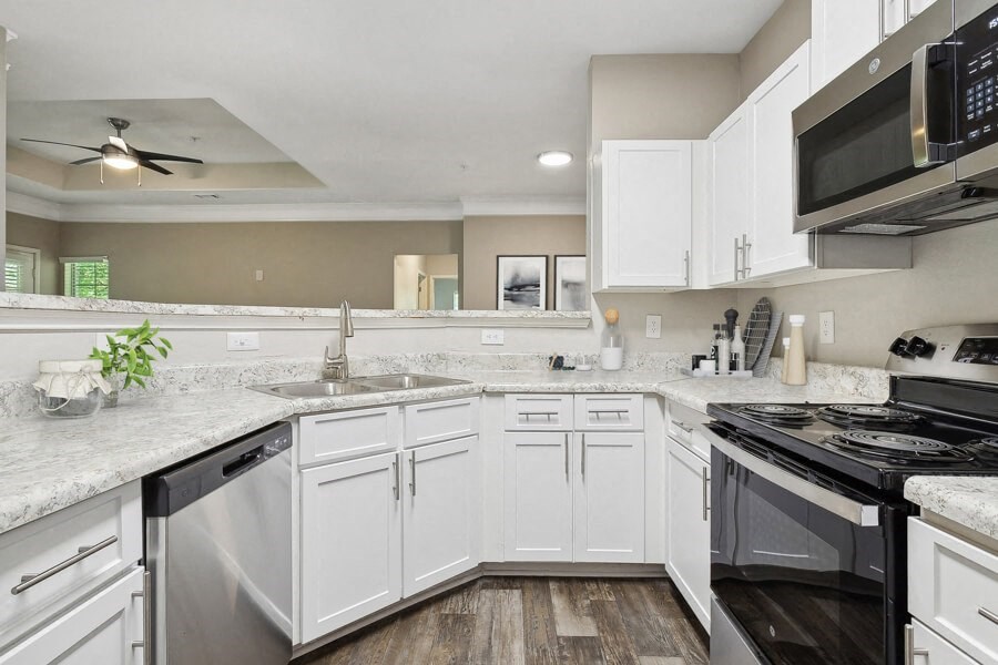 Model apartment kitchen with white cabinets and a stove and a microwave