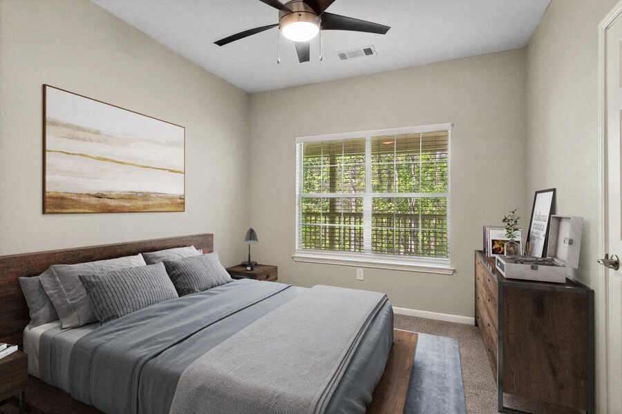 Model apartment bedroom with a bed and a ceiling fan