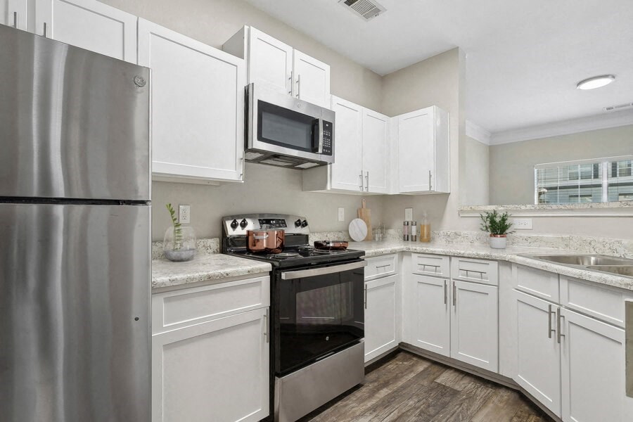 Model apartment kitchen with stainless steel appliances and white cabinets