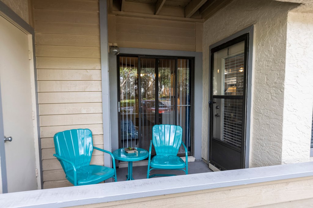 Blue chairs and a table on a porch  at Huntington Place Apartments in Sarasota, Florida