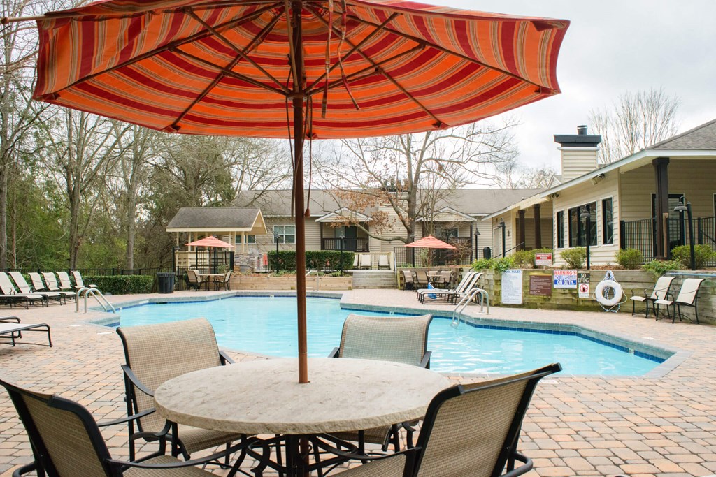 Community pool and a patio with chairs and an umbrella