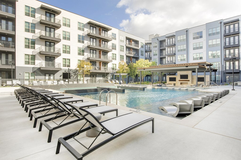a swimming pool with lounge chairs in front of an apartment building