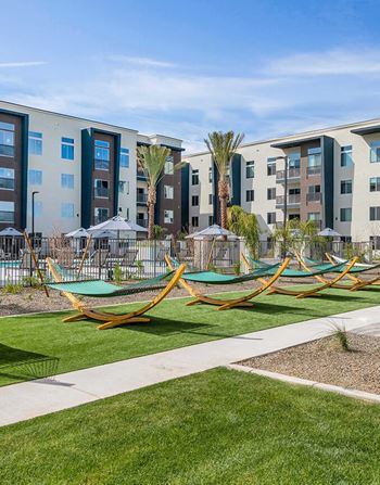 a group of hammocks on the grass in front of some apartments