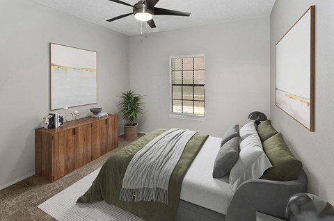 1 Bedroom Luxury Apartments in North Dallas, TX - Dallas North Park - A Bedroom With Wood Bed Frame, Ceiling Fan, Soft Bedding, Wall Art, And Window With Blinds.
