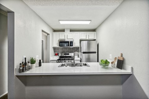 a white kitchen with a sink and a refrigerator
