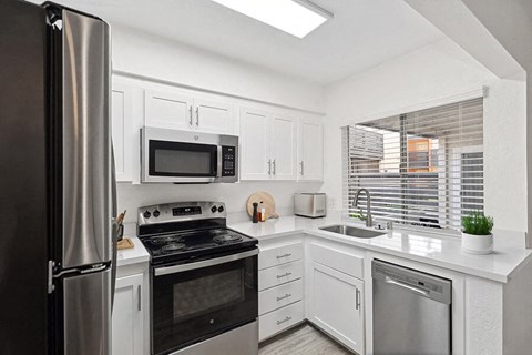 A modern kitchen with white cabinets and stainless steel appliances.