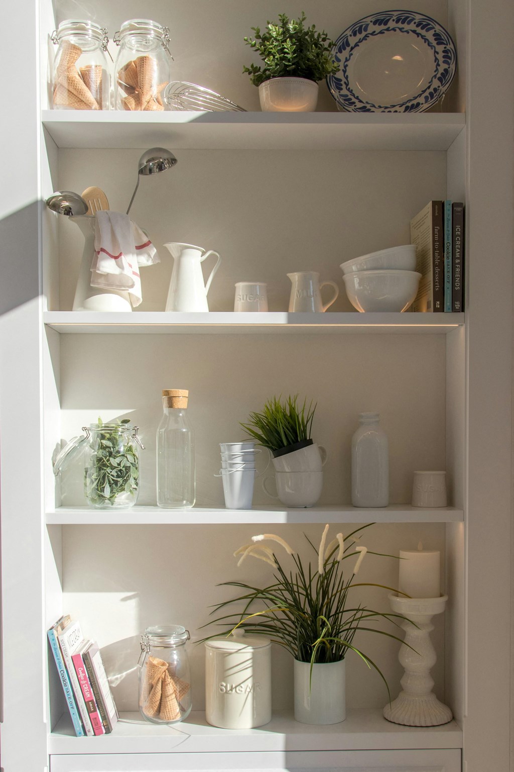 a shelving unit with ceramics and plants on it