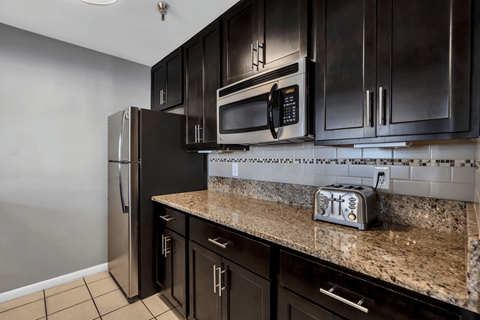 A kitchen with black cabinets and a granite countertop.