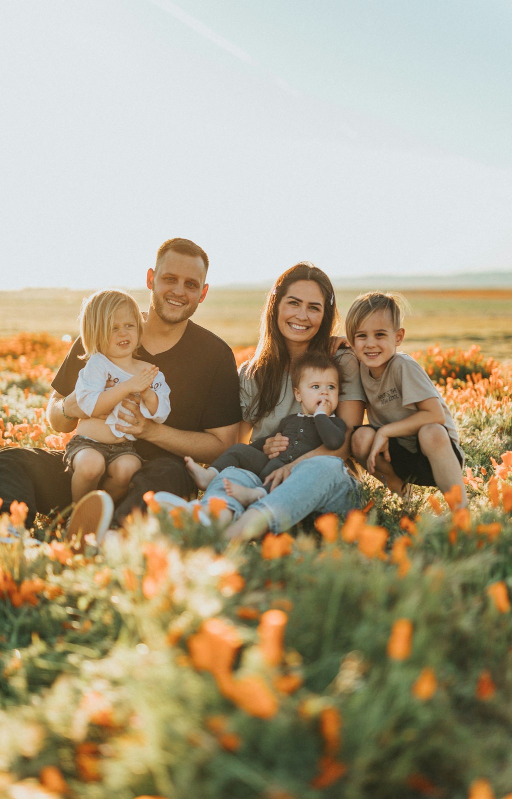 a portrait of a family sitting in a field of flowers