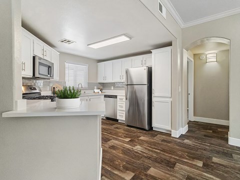 A kitchen with white cabinets and a wooden floor.