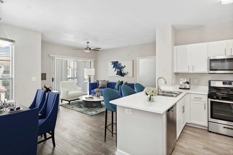 A modern kitchen with blue chairs and white cabinets.