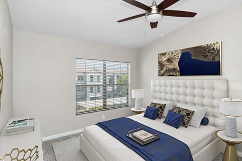 Apartments in North Las Vegas, NV, with In-Unit Washer and Dryer - Azure Apartment Homes - Bright Bedroom With Tufted Headboard, Ceiling Fan, Blue Bedding, And Large Window With Blinds.