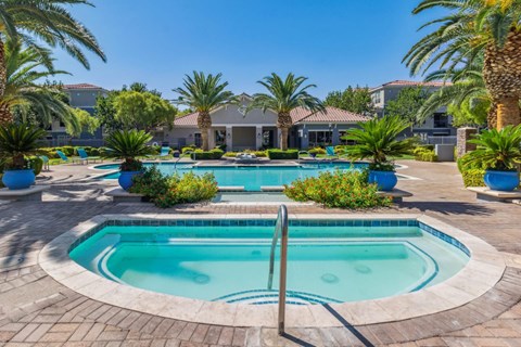 North Las Vegas, NV, Apartments Near Las Vegas Strip - Azure Apartment Homes - Swimming Pool And Spa With Palm Trees, Lounge Chairs, And Clubhouse Courtyard Under Blue Sky.