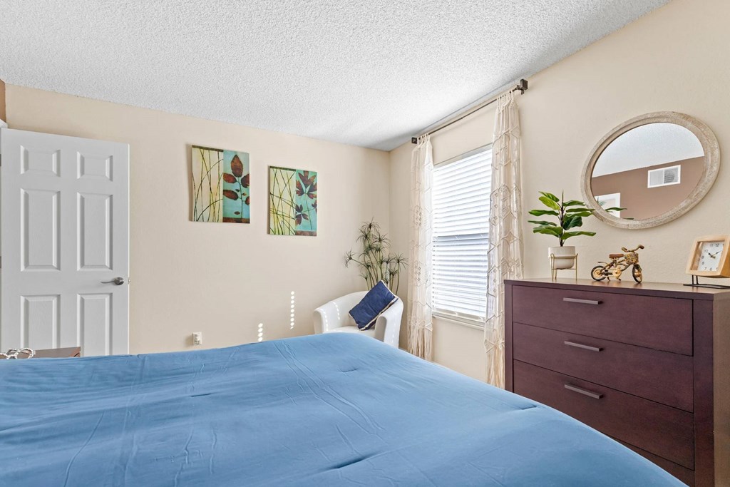A bedroom with a blue bedspread and a white door.