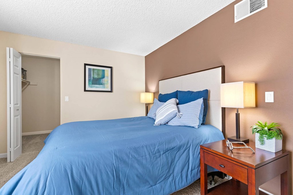 A bedroom with a blue bedspread and a white pillow.