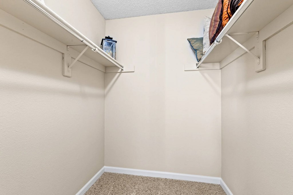 A small, empty room with a carpeted floor and two white shelves.