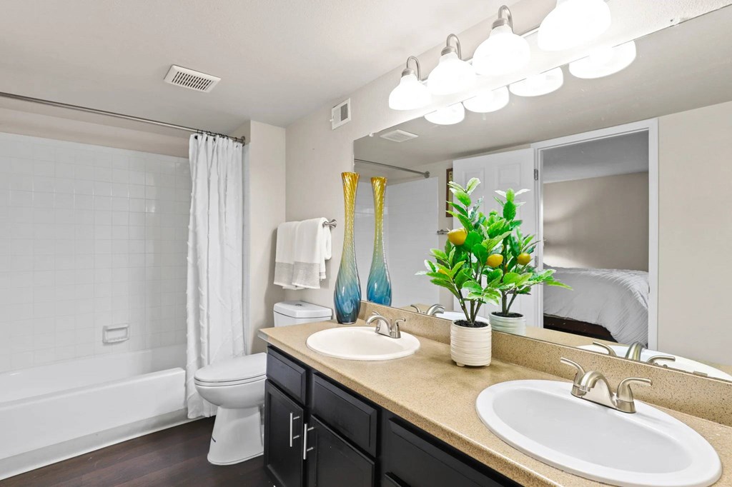 A bathroom with a white tub, sink, and mirror.