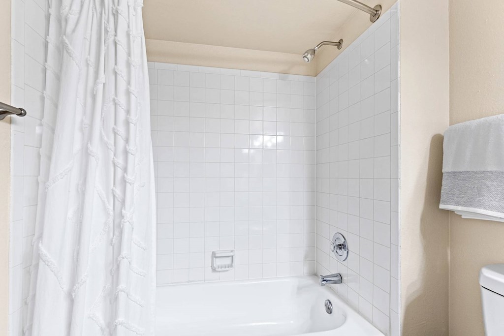 A white bathroom with a white tub and shower curtain.