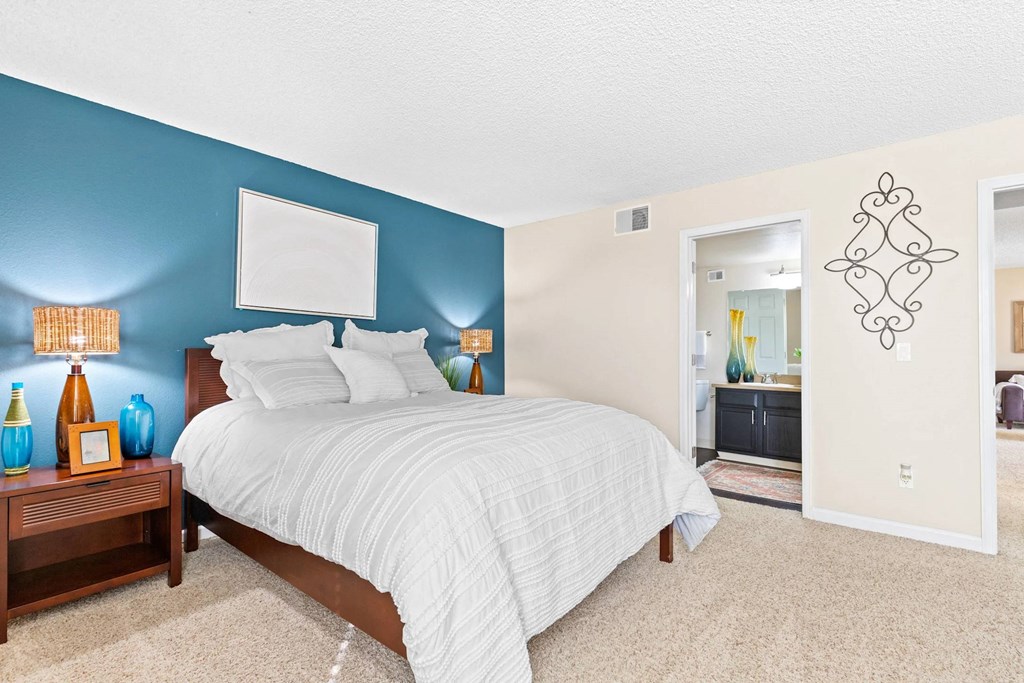 A bedroom with a bed, nightstand, and a wall art.