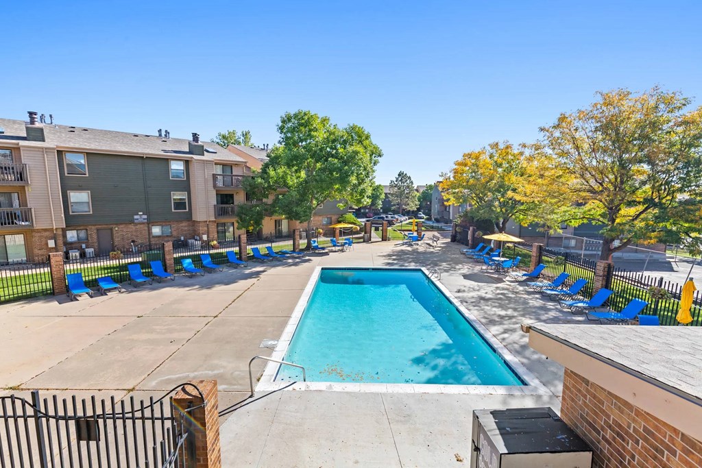 A swimming pool surrounded by blue chairs and apartment buildings.