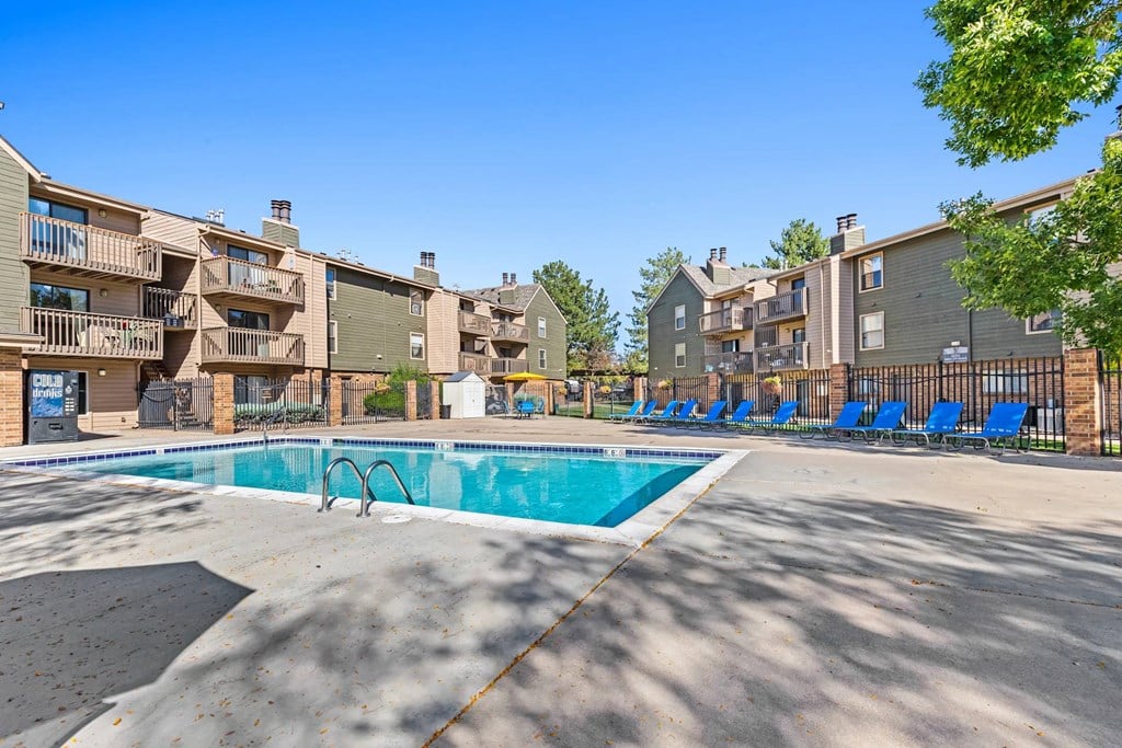 A swimming pool surrounded by apartment buildings on a sunny day.