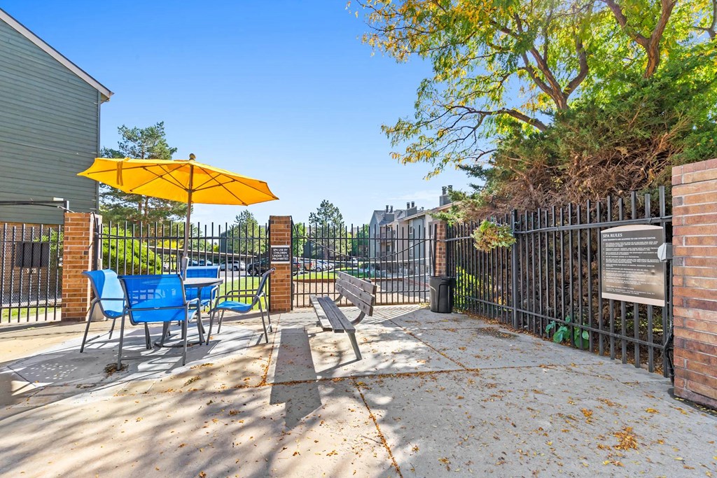 A yellow umbrella is on a blue chair on a patio.