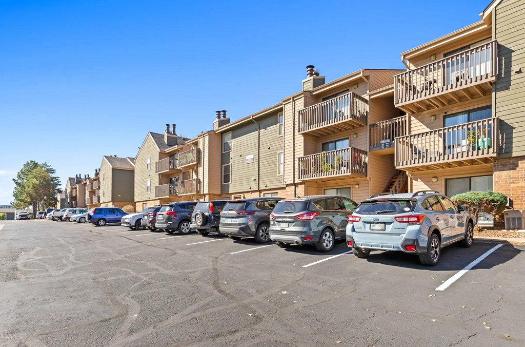 A parking lot with cars and apartment buildings in the background.