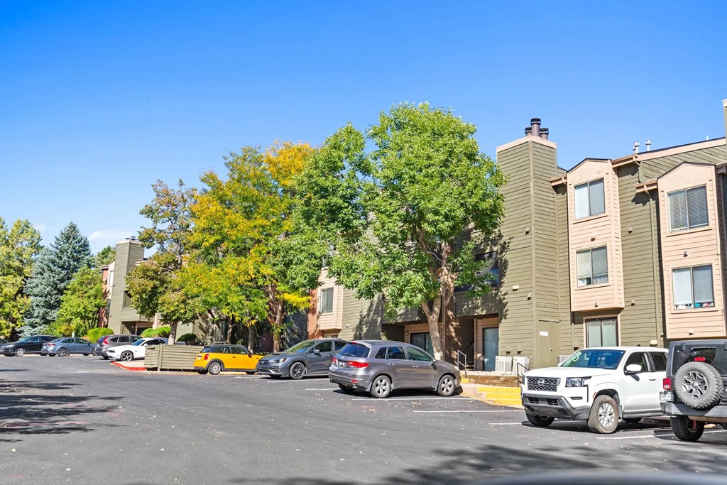 A parking lot with cars and apartment buildings in the background.