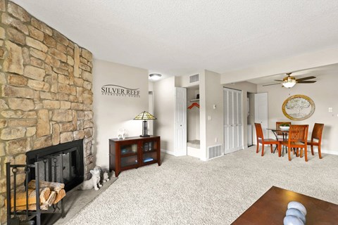 A living room with a stone fireplace and a dining table with chairs.