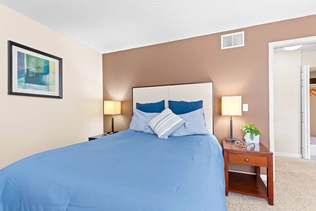 A bed with a blue cover and two blue pillows is in the image.
