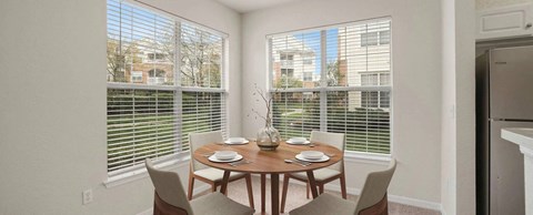 A dining room with a table set for two and a view of the outside.