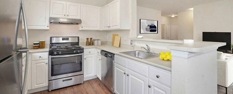 A white kitchen with a stainless steel refrigerator and oven.