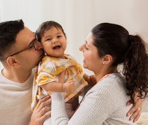 a mother holding a baby and a father kissing a baby