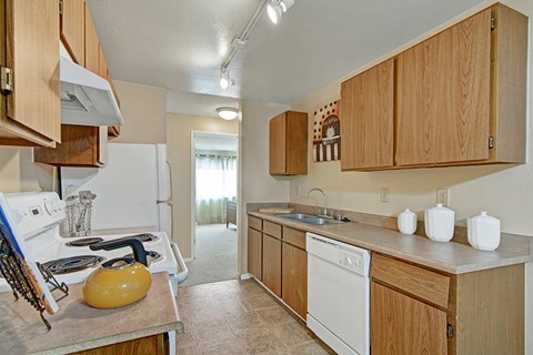 A kitchen with a white stove top oven and white dishwasher.